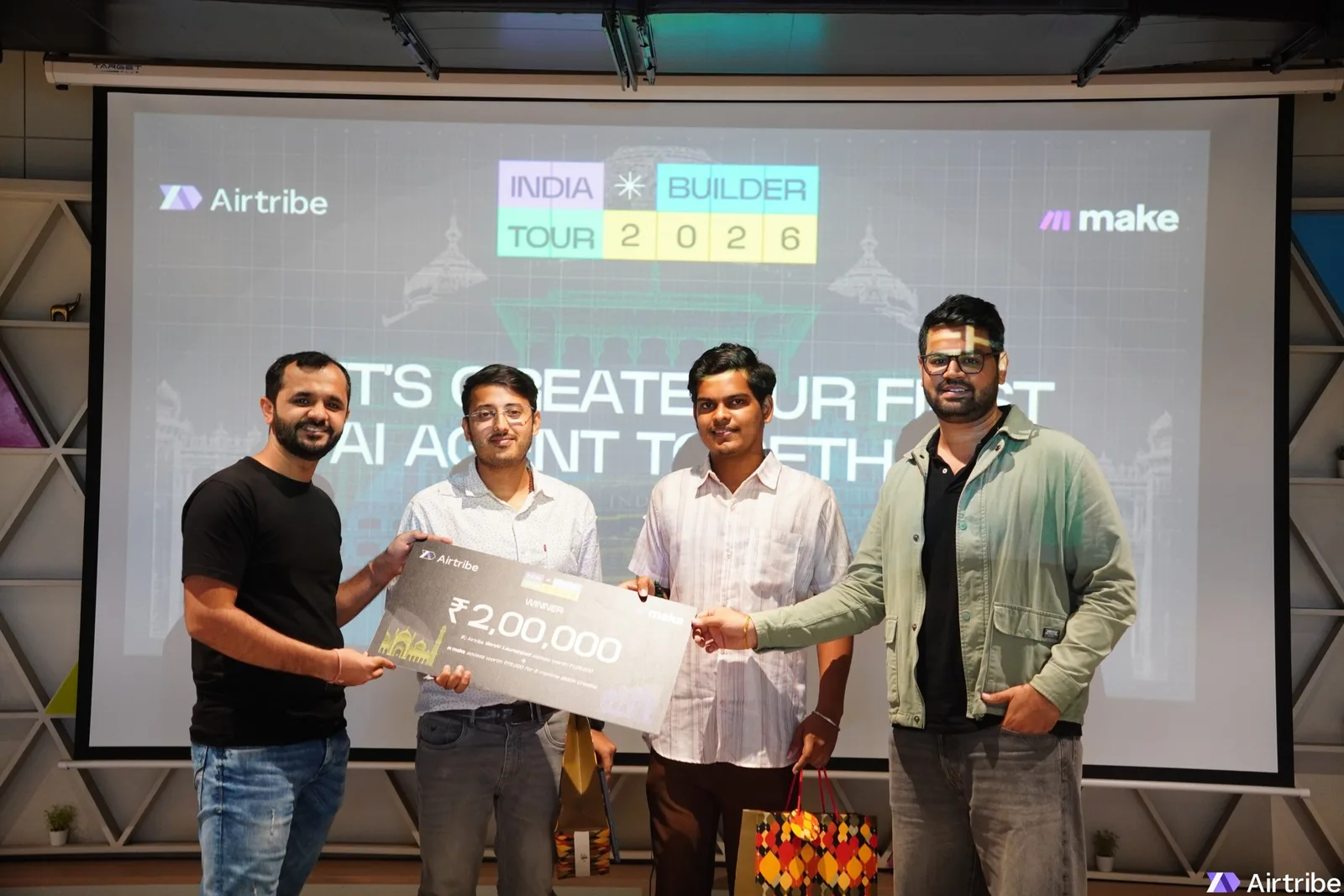 Four men on stage holding the winner's cheque at the India Builder Tour 2026, an Airtribe and Make event in Ahmedabad. Aryan Tripathi is second from the left, in the white shirt.